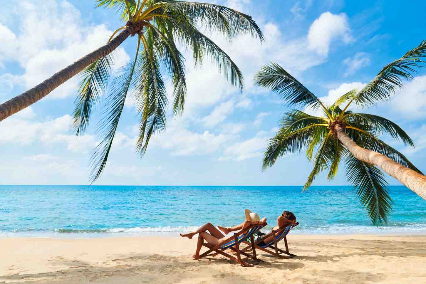 Couple on a beach with palm trees during vacation, relaxing tropical seaside getaway